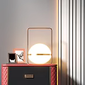 Stylish Nightstand With Red Quilted Sides Two Drawers Gold Handles Round Lamp And Photo Frames On Top