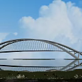 Modern Arch Bridge Design Over Water With Reflective Surface Green Grass And Blue Sky