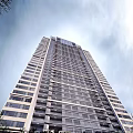 Tall Modern High Rise Building With Multiple Floors And Windows Against Blue Sky