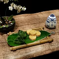 Traditional Chinese Zongzi and Mooncakes on Reed Leaves with Bamboo Tray and Porcelain Vase