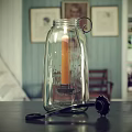 Glass Jar Candle Lamp With Lit Candle And Engraved Text On Blue Wall Background