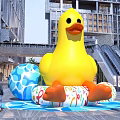 Outdoor Photo Spot with Giant Yellow Inflatable Duck and Colorful Rings Near Modern Buildings