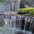 Multi Tiered Water Fountain With Flowing Water Surrounding Greenery Background Wall And Trees