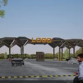 Modern Entrance Gate with Geometric Canopy Glass Roof and Prominent Logo Sign Surrounded by Trees
