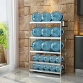 Stainless Steel Multi Tier Storage Rack With Blue Water Jugs In Kitchen Against Brick Wall