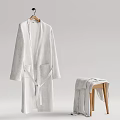 Soft White Long Robe Hanging On Wooden Hanger With Folded Towel On Stool