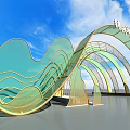 Event Gateway Green And Gold Wavy Arch Design With Glass Structure Under Blue Sky