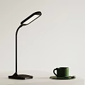 Modern Black Desk Lamp With Curved Arm And Green Cup On Tabletop