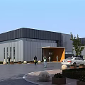 Modern Industrial Factory Building With Metal Exterior Gray Roof Entrance Parking Area And Trees