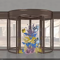 Activity Entrance With Brass Revolving Door Glass Panels And Decorative Floral Arrangement