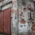 Old Industrial Factory Building with Weathered Roof Red Brick Plaster Walls Peeling Sections and Green Door
