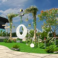 Outdoor Decorated Arch With Green Plants Bloomville Sign And White Circular Decor On Lawn