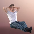Man sitting with hands behind head in white t-shirt and plaid pajamas on pink background