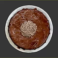 Red Round Cake With Shiny Red Glaze Topped With Crushed Nuts On White Plate