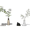White Vases Holding Green Branches Alongside Books Elephant Figurine And Stone On Minimalist Gray Background