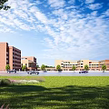 Red Brick School Buildings With Green Lawn Trees And Open Blue Sky View