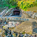 Natural Rocky Cliffside with Cave Entrance Stone Steps and Waterfront Green Vegetation