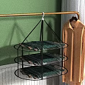 Three Tiered Metal Clothes Hanger Holding Folded Clothes with Shirt Hanging Nearby in Indoor Space