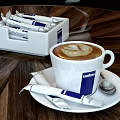 Lavazza Steaming Coffee Cups With Latte Art And Sachets On Wooden Table