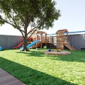Garden Landscape with Wooden Roof Stone Wall Patio Dining Area Playground and Sunlit Lawn
