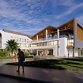Modern Public Building With White Exterior Wooden Roof Glass Windows Green Lawn And People
