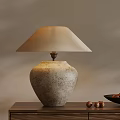 Textured Stone Base Table Lamp With Cream Fabric Shade On Wooden Table