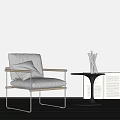 Beige Upholstered Accent Chair With Metal Frame And Side Table With Candles And Open Books