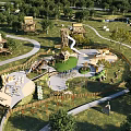Outdoor Natural Playground with Green Grass Trees Play Structures Slides and Winding Paths