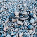 Colorful Natural Stone And Wood Pebbles Stacked By Water Edge For Decoration
