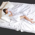 Woman Resting Comfortably On Bed With White Bedding And Pillows