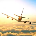 Passenger Airplane Flying Over Golden Clouds in Bright Sunrise Sky