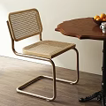 Modern Woven Dining Chair With Metal Frame And Wooden Table With Oranges