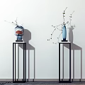 Blue and Red Vases with Flower Branches on Black Pedestals Against White Wall