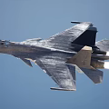 Fighter Jet Flying High In Blue Sky With Jet Engine Exhaust Flames
