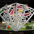 Modern Exhibition Booth With Curved White Framework Colorful Decorations Display Counters And Green Plants