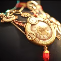 Elegant Gold Jewelry Set on Black Mannequin with Red Ribbon Decorative Pendants and Circular Chains