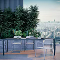 Modern Outdoor Table With Rattan Chairs And Leafy Plants Overlooking City Skyline