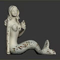 Mermaid Statue With White Body Brown Spots And Blue White Tail Sitting On Black Surface