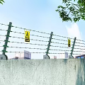 Industrial Security Barbed Wire Fence With Green Insulators Yellow Warning Signs And Concrete Base