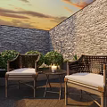 Cozy Outdoor Table With Rattan Chairs Candle And Bushes Against Stone Wall At Sunset