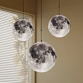Three moon shaped pendant lights hanging by window with white blinds indoor