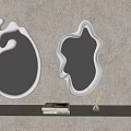 Two Irregular Shaped Silver Mirrors on Gray Wall with Shelf Books and Small Plant