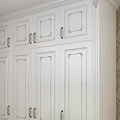 White Wardrobe in Room Corner with Brown Patterned Wallpaper and Wooden Floor