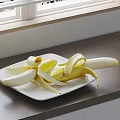 Fresh Peeled Banana on White Plate on Wooden Countertop Near Window