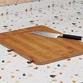 Bamboo Cutting Board With Sharp Knife On Colorful Speckled Kitchen Countertop