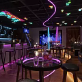 Stylish Modern Bar Interior Featuring Neon Lights Bar Counter Round Tables And Ambient Lighting