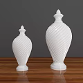 Two White Ceramic Vessels with Spiral Patterns on Wooden Tabletop Against Gray Background