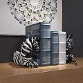Decorative Books in Blue Silver with Zebra Figurines and Wall Art on Wooden Surface