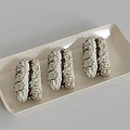 Three Delicious Macarons With White Frosting And Chocolate Drizzle On Ivory Rectangular Plate