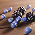 Fresh Ripe Peaches in Blue Bowl with Blackberries Blueberries and Honey Jar on Wooden Table